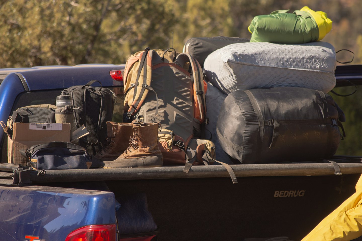 Blue pickup truck bed packed with camping gear for an adventure.